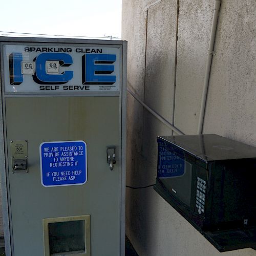 The image shows an ice vending machine along with an AC unit installed on the right wall, situated in a partially enclosed area.