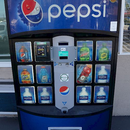 A Pepsi vending machine with various drink options, a central payment area, and a visible dispenser at the bottom.