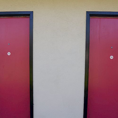 The image shows two red doors with black frames labeled 106 and 107, each with a peephole and a modern handle with electronic locks.