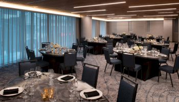 This image shows a banquet hall set up with round tables, each decorated with place settings, glassware, and small floral arrangements.