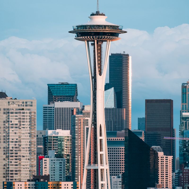 The image shows the Space Needle, an iconic observation tower in Seattle, with the city's skyline and various skyscrapers in the background.